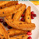 Pinterest pin with text overlay "Orange Cranberry Biscotti', image of a white plate piled with biscotti.