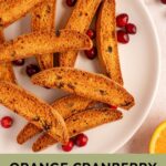 Pinterest pin with text overlay "Orange Cranberry Biscotti', image of a white plate piled with biscotti.
