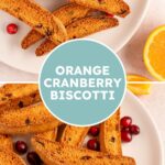 Pinterest pin with text overlay "Orange Cranberry Biscotti', image of a white plate piled with biscotti.