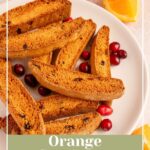 Pinterest pin with text overlay "Orange Cranberry Biscotti', image of a white plate piled with biscotti.