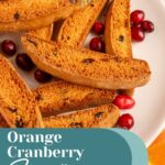 Pinterest pin with text overlay "Orange Cranberry Biscotti', image of a white plate piled with biscotti.