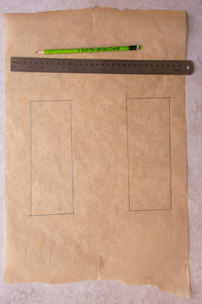 A piece of brown parchment paper with 2 rectangles drawn on with a pencil and ruler.