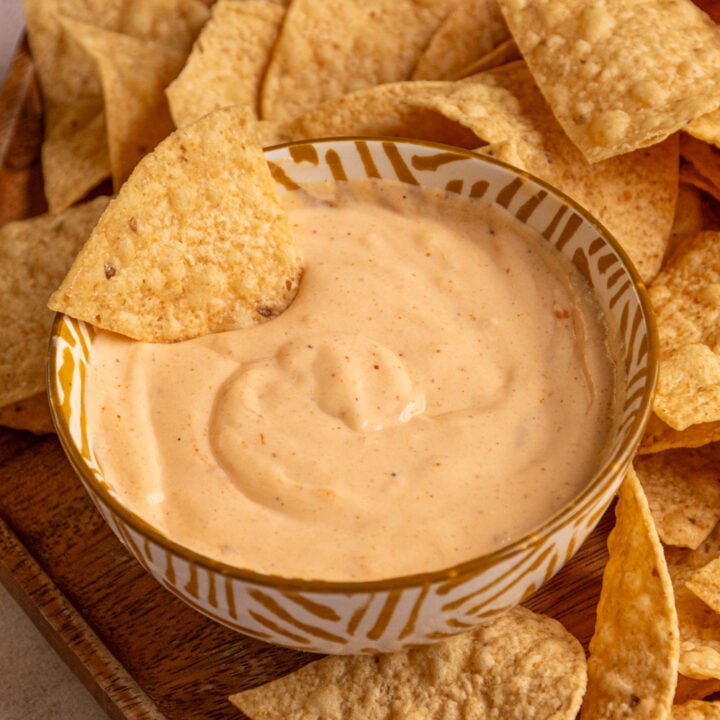 A small bowl with cottage cheese queso with a chip dipped into it.