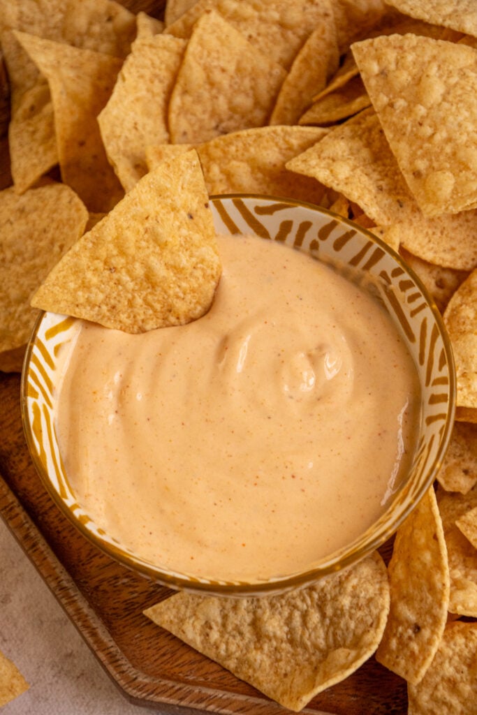 Overhead of a small bowl with yellow cottage cheese queso with a chip in it.