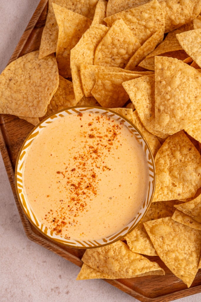 Overhead view of a platter of chips and a small bowl of cottage cheese queso.