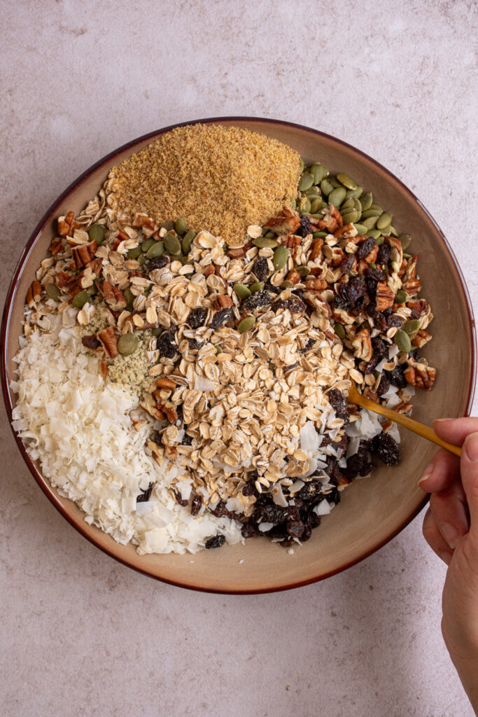 Mixing together the oats, nuts, seeds, and dried fruit to make muesli.