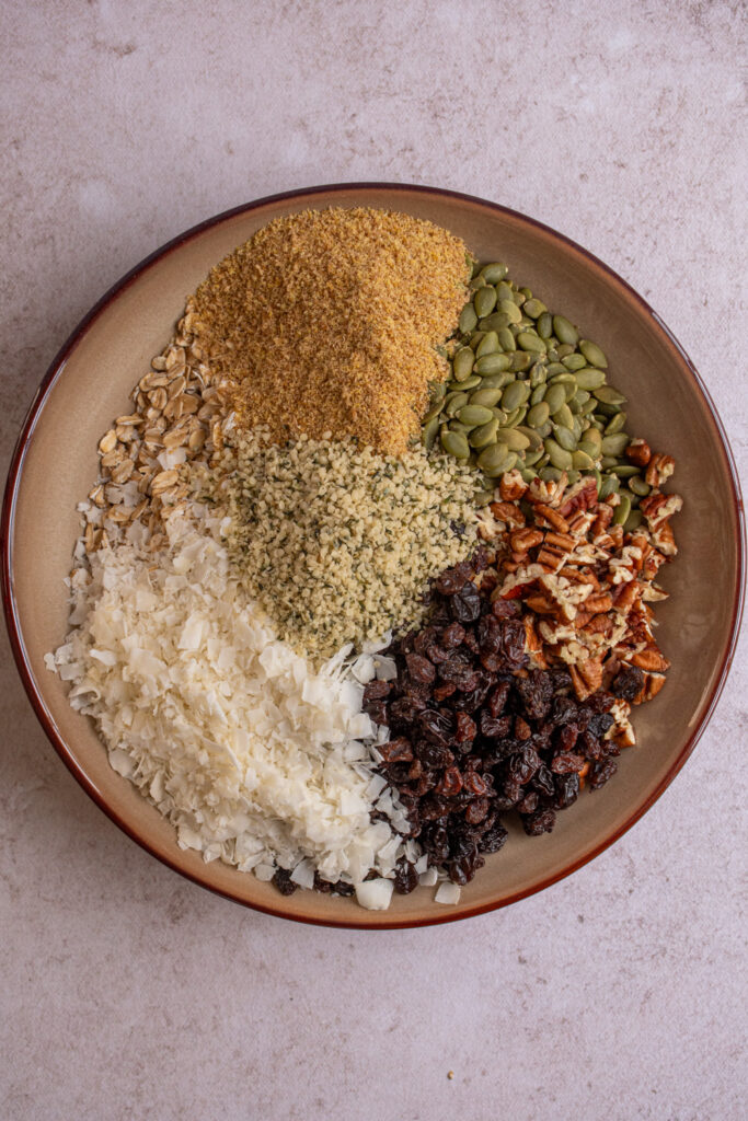 Making muesli being adding together all the oats, nuts, seeds, and dried fruit to a bowl.