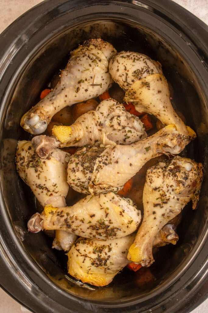 The slow cooker doe cooking the chicken legs and vegetables.