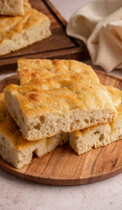 Pieces of focaccia bread on a wooden plate.