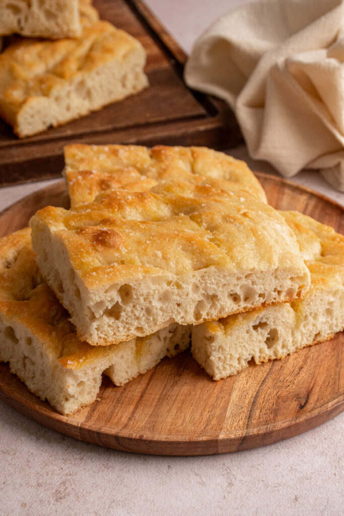 Pieces of focaccia bread on a wooden plate.