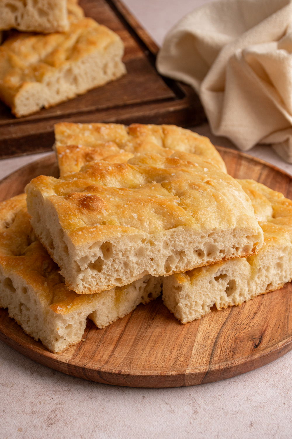 Pieces of focaccia bread on a wooden plate.