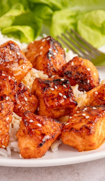A serving of honey garlic salmon bites on top of a bed of white rice.