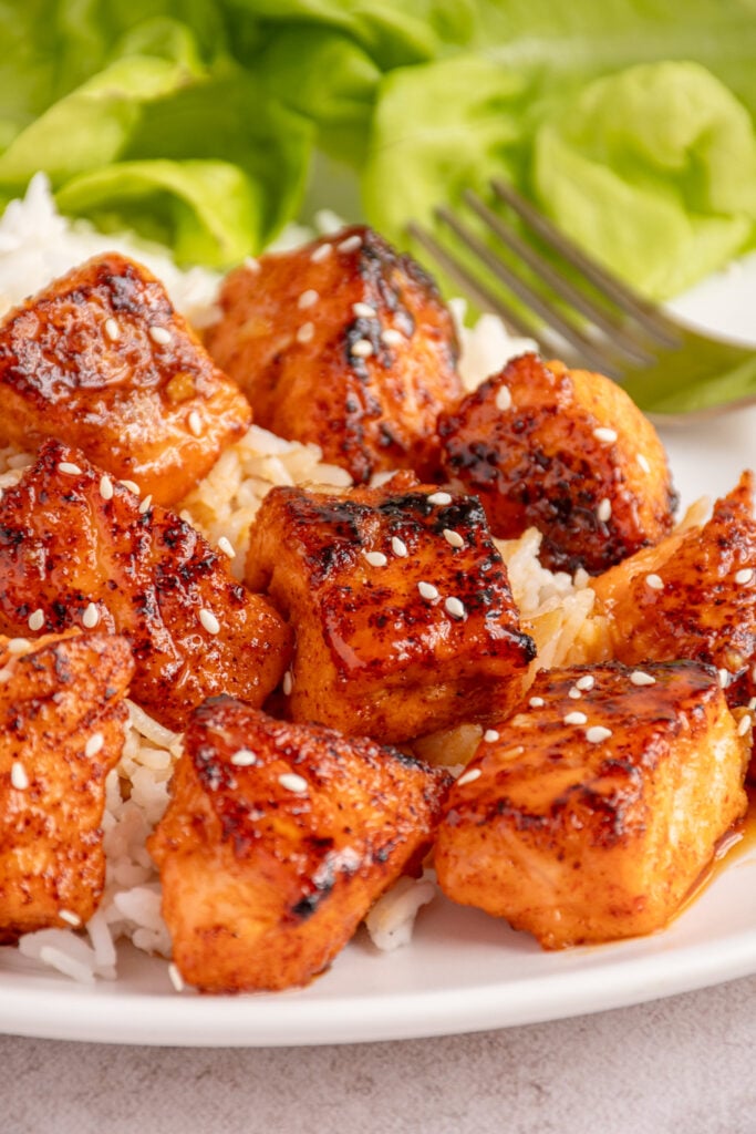 A serving of honey garlic salmon bites on top of a bed of white rice.