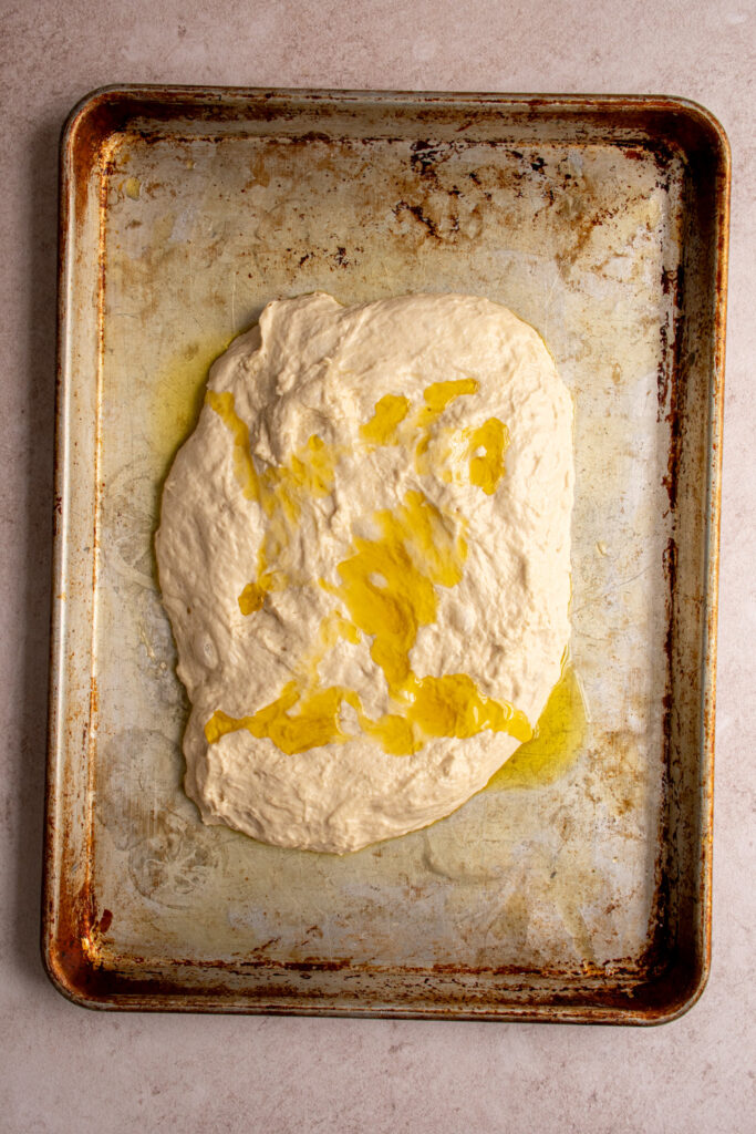 Olive oil drizzled over the top of the focaccia dough.