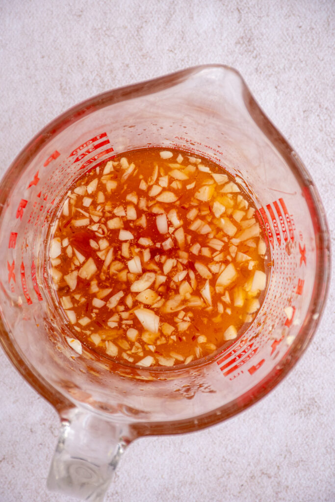 Honey garlic sauce in a glass measuring cup.