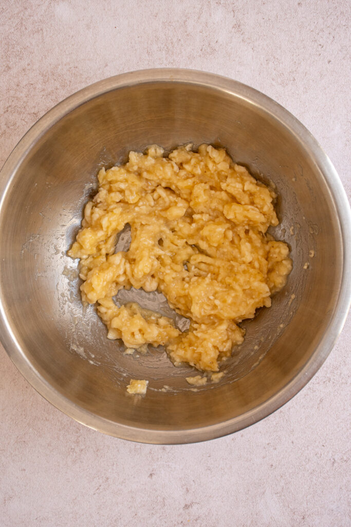 Mushed bananas in a bowl for making Banana Chocolate Chip Pancakes.
