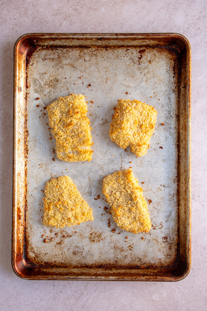 Freshly baked crispy pieces of fish on a sheet pan.