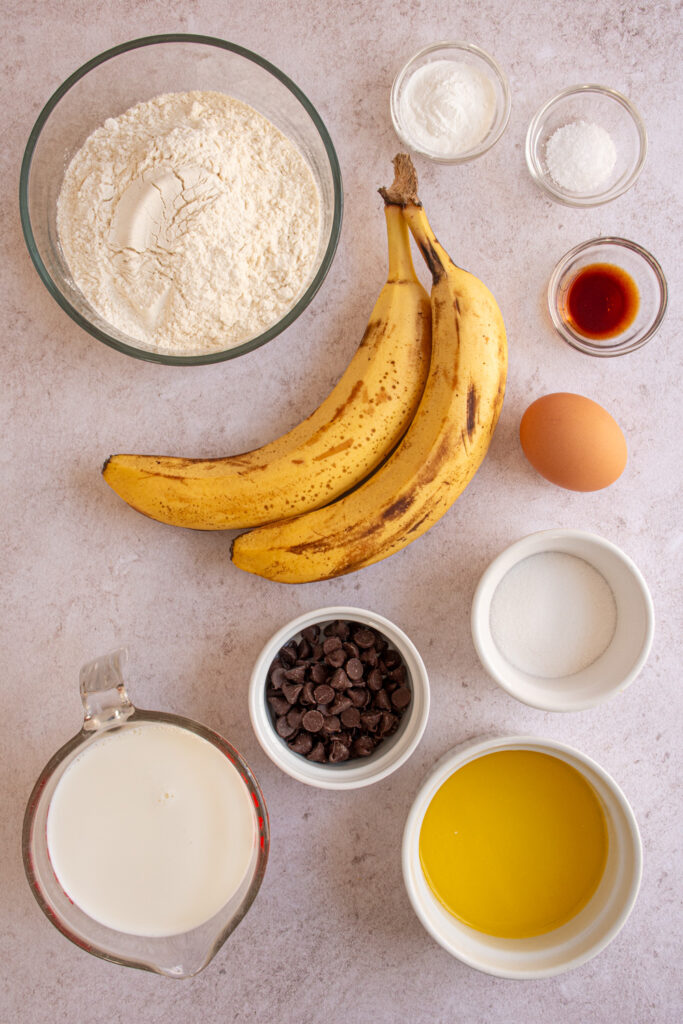 Ingredients for making Banana Chocolate Chip Pancakes laid out on a tabletop.