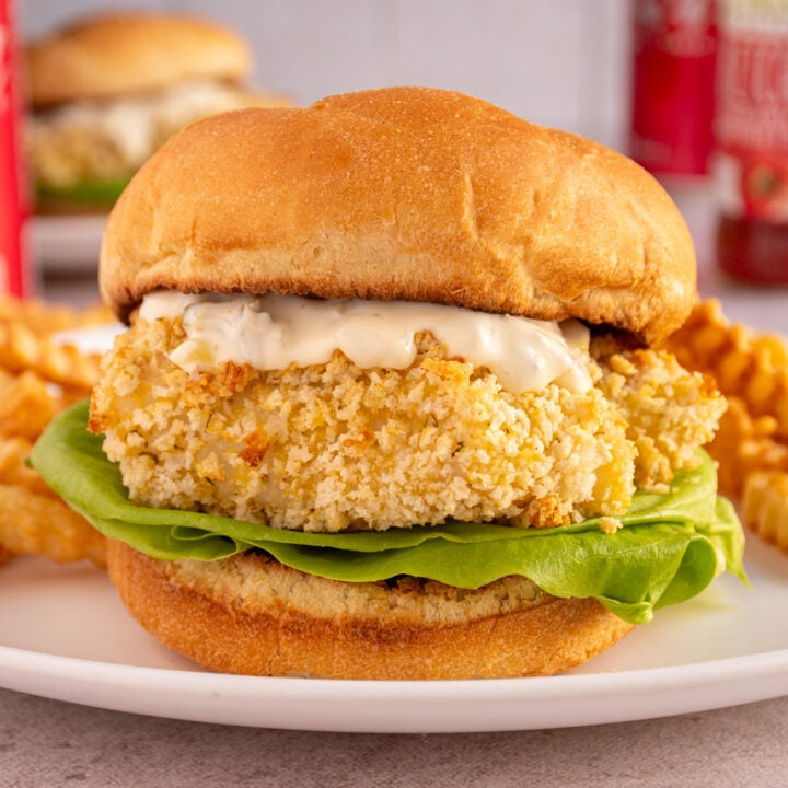 A soft bun with baked fish fillet, tartar sauce, and lettuce.