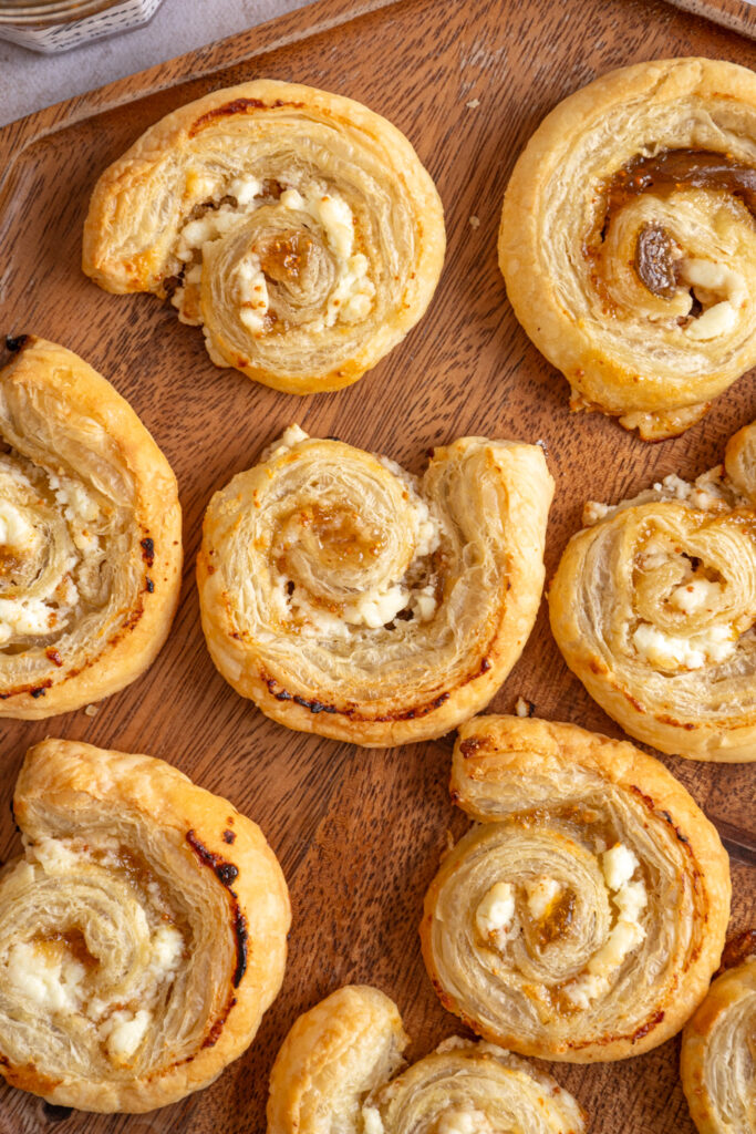 A wood tray filled with Fig and Goat Cheese Puff Pastry Pinwheels.