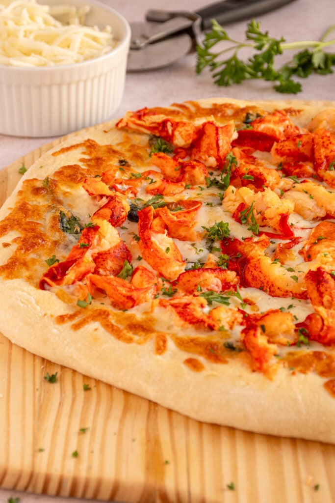 Angle of a lobster pizza on a wooden pizza peel.