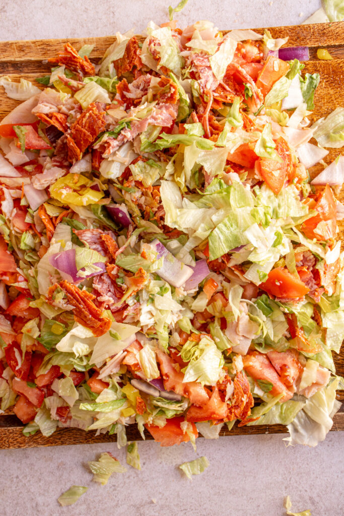 The chopped ingredients on a wood cutting board for making Chopped Italian Sandwiches.