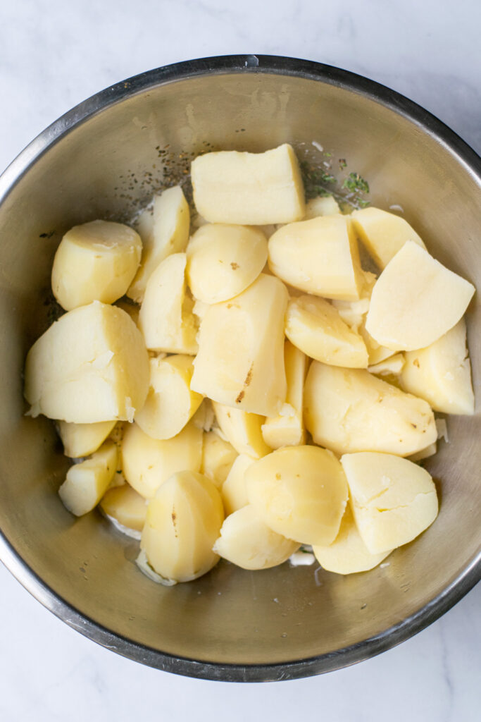 freshly cooked potatoes in a stainless steel bowl ready to be mashed