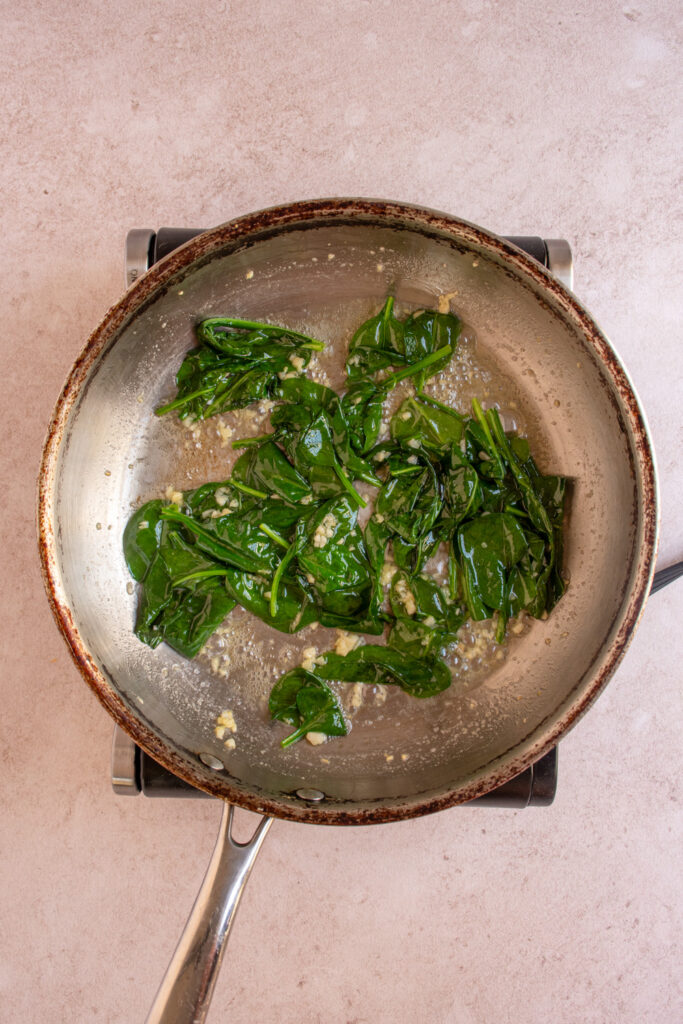 A skillet with butter, garlic, and wilted spinach.