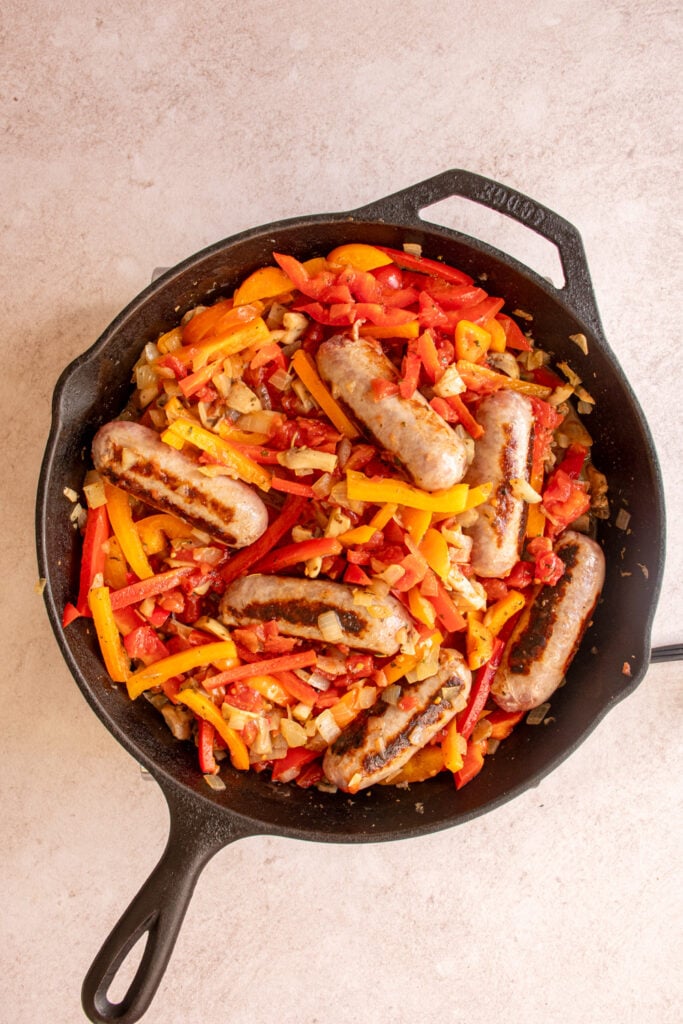 Cooking the sausages with the peppers in a large skillet.
