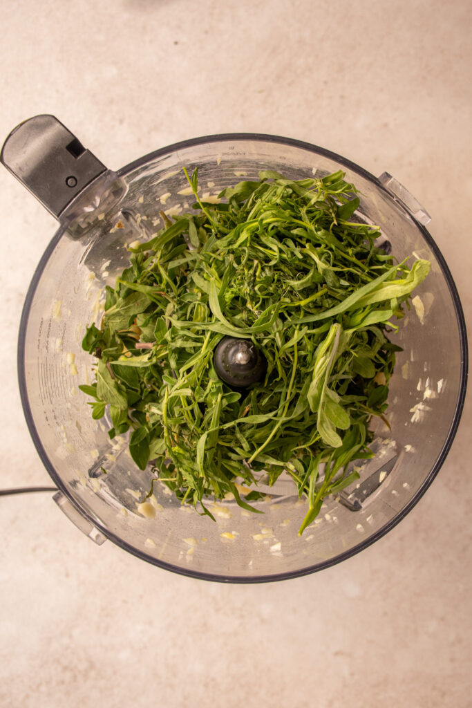 Fresh tarragon, oregano, and garlic in a food processor.