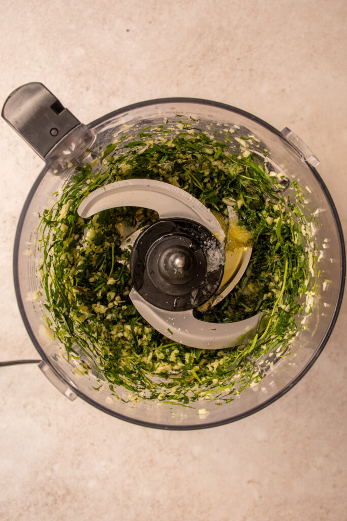 Minded herbs and garlic with added olive oil, lemon juice, and salt to a food processor.