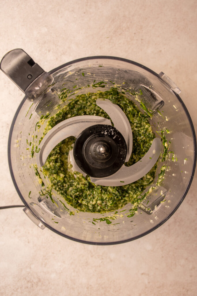 Herbs and garlic mixed with olive oil in the food processor for putting on the raw chicken.