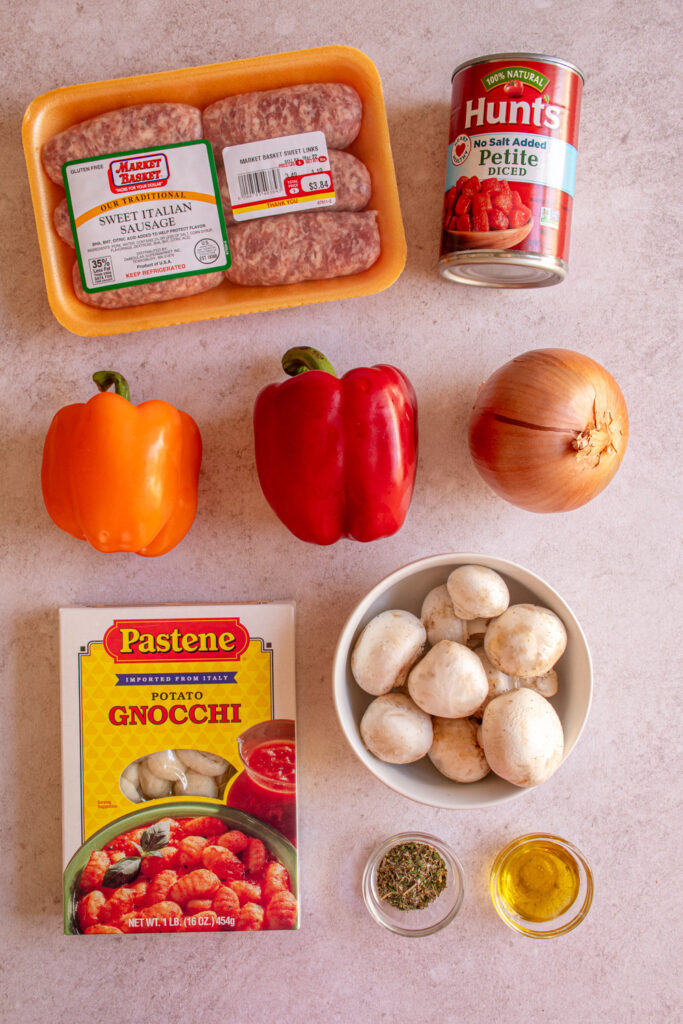 Ingredients to make gnocchi with sausages and peppers laid out on a table top.