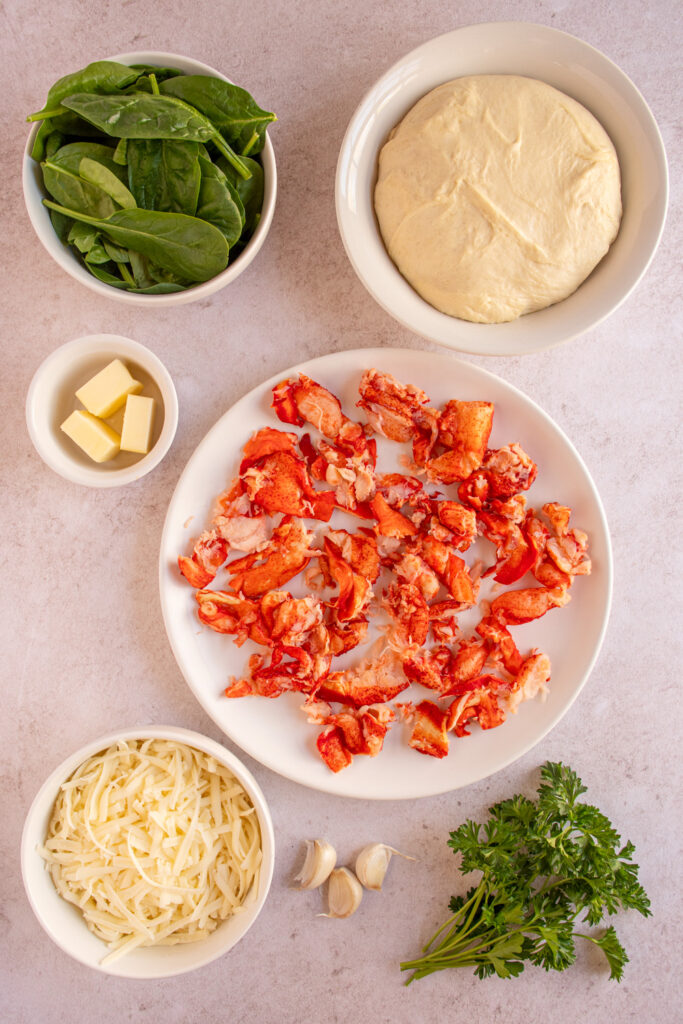 Ingredients to make a lobster pizza recipe laid out on a table top.