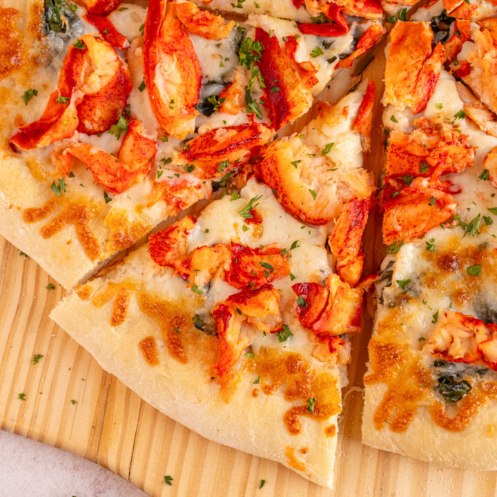 A slice of lobster pizza on a wooden pizza peel.