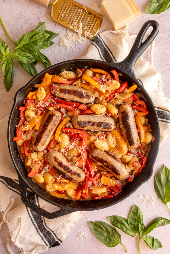Overhead view of a large skillet with bell peppers, sausage, and gnocchi.