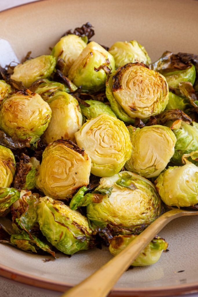 A brown serving bowl filled with crispy air fryer brussel sprouts.