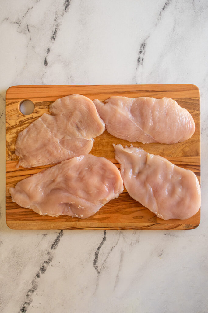Two large chicken breasts cut horizontally into four chicken cutlets.