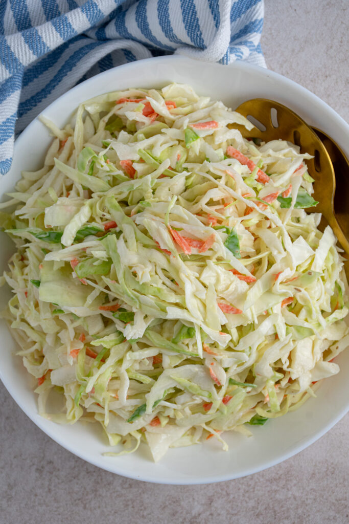 Overhead view of a white serving bowl filled with coleslaw recipe without celery seed.