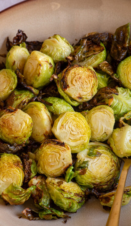 Crispy brussel sprouts cooked in an air fryer in a brown bowl.