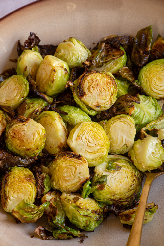 Crispy brussel sprouts cooked in an air fryer in a brown bowl.