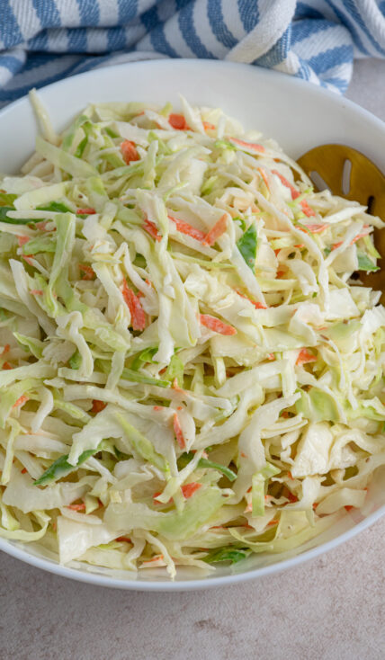 A large white serving bowl filled with green coleslaw recipe without celery seed.