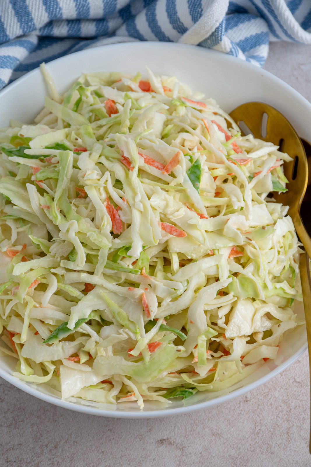 A large white serving bowl filled with green coleslaw recipe without celery seed.