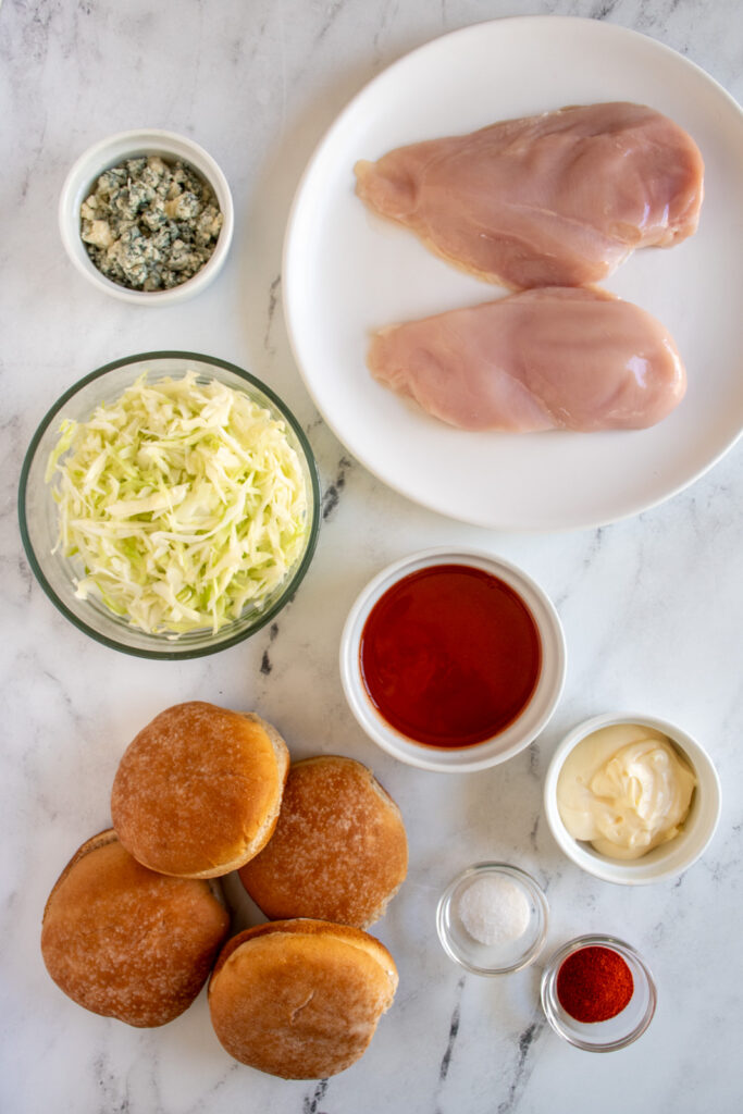 All the ingredients needed to make grilled buffalo chicken sandwiches laid out on a tabletop.