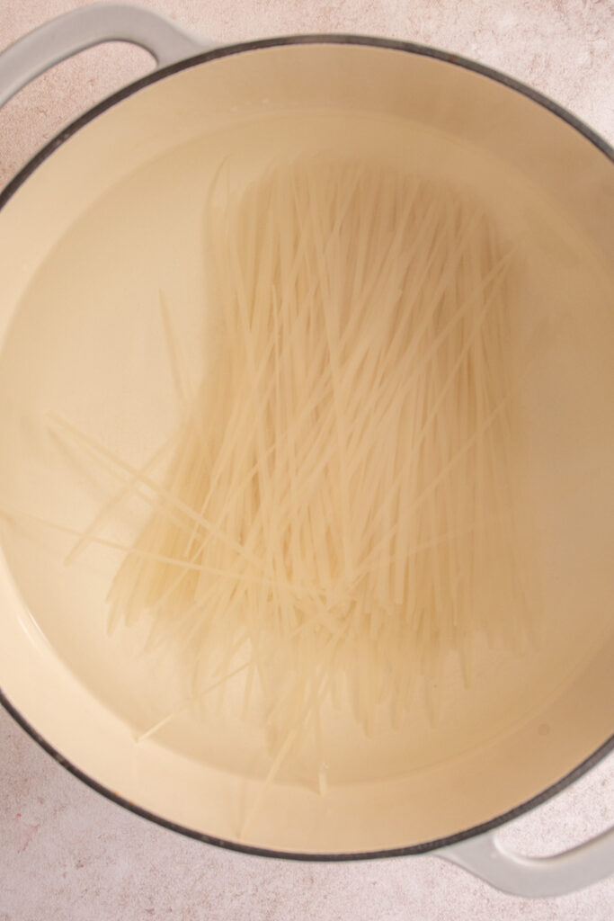 Rice noodles added to a large pot of water.