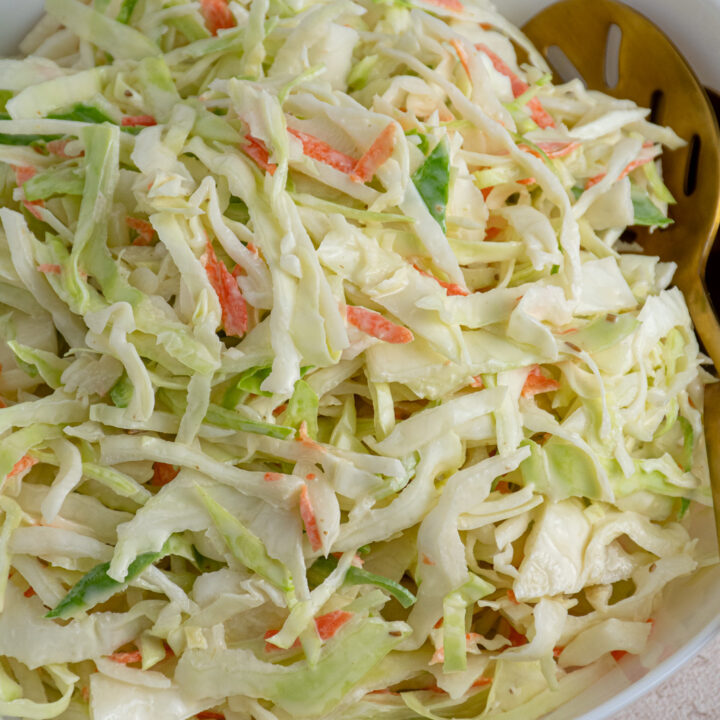 A white serving bowl filled with freshly made coleslaw recipe without celery seed.