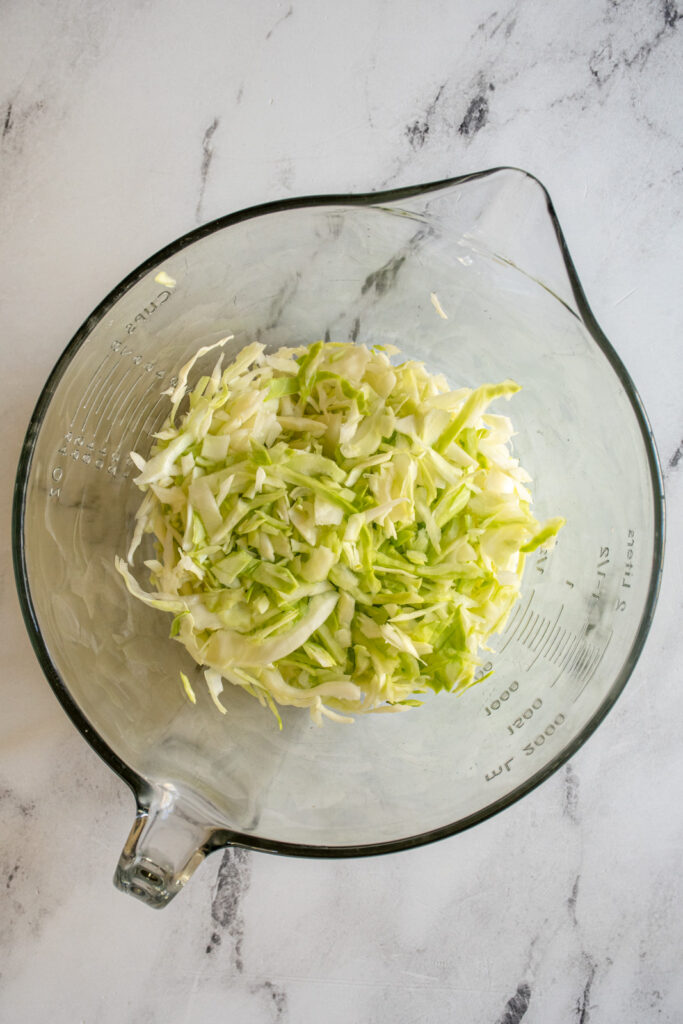 A white bowl filled with shredded cabbage.