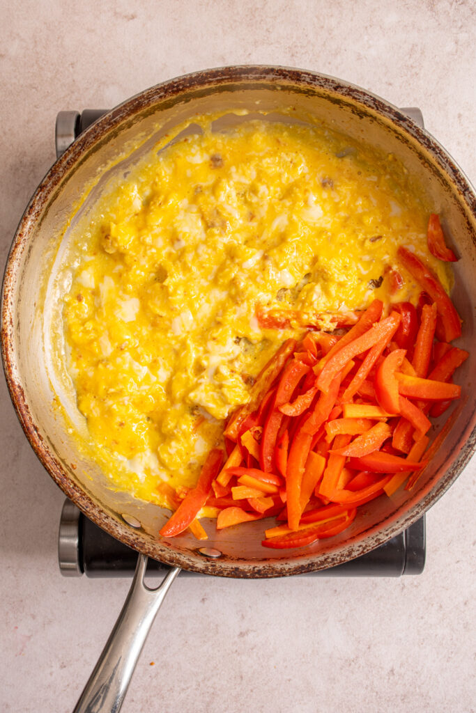 The veggies pushed to one half of the skillet with the scrambled eggs on the other half.