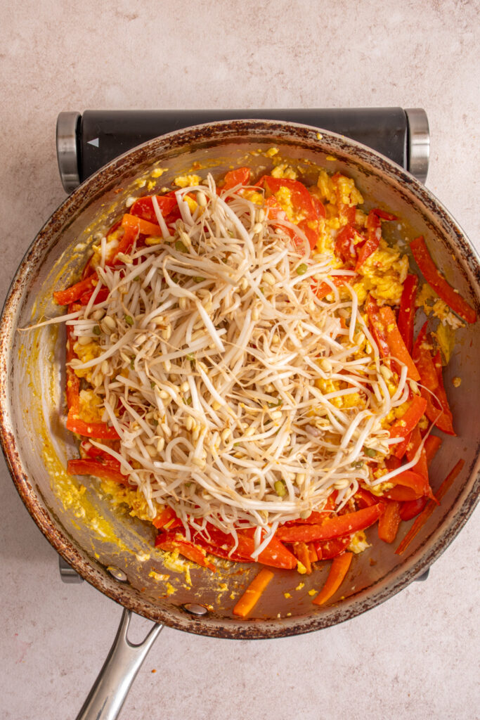 Adding bean sprouts to the skillet with the veggies and scrambled eggs.
