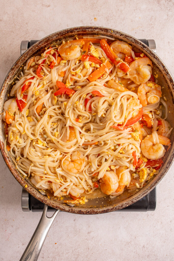 A photo of the freshly made finished shrimp pad thai in a large skillet with noodles, shrimp, and vegetables.